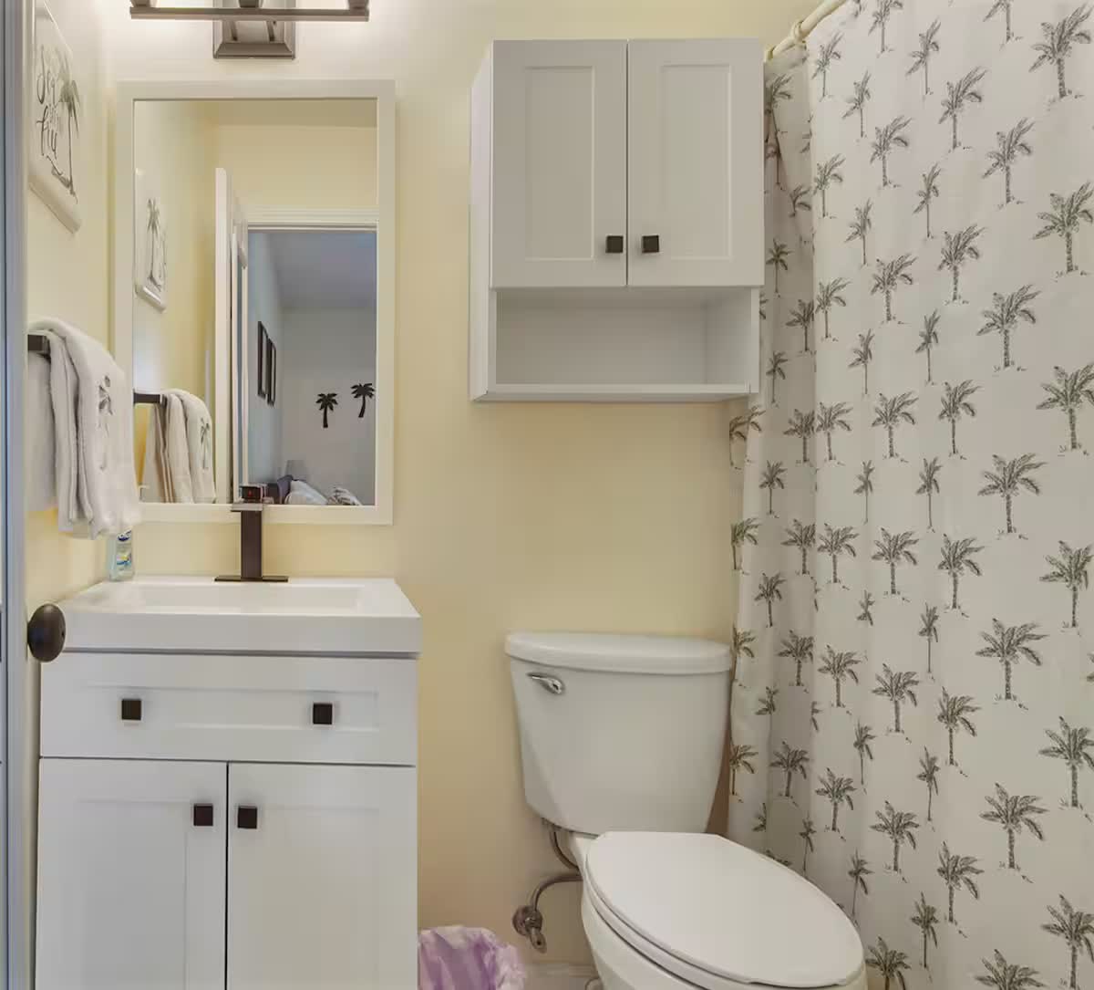 Bathroom with palm-tree shower curtain and white vanity