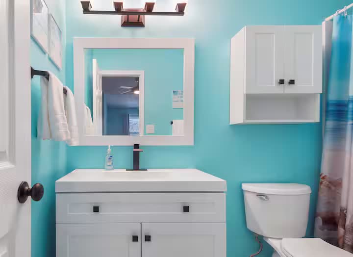 Turquoise bathroom vanity with white cabinets and framed mirror