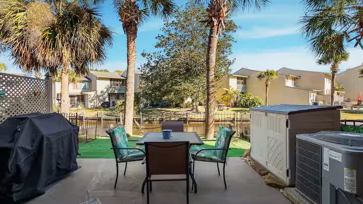 Private patio with outdoor dining table, grill, and palm trees