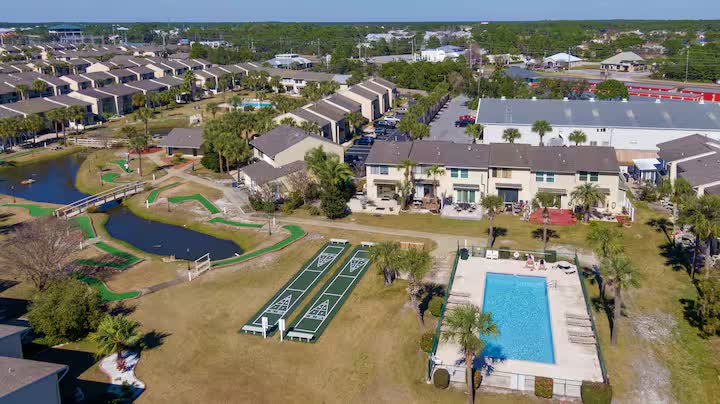 Aerial view of the resort with a pool, mini golf course, shuffleboard courts, and pond