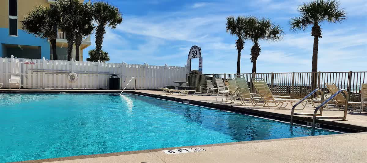 Resort pool with lounge chairs and palm trees overlooking the Gulf