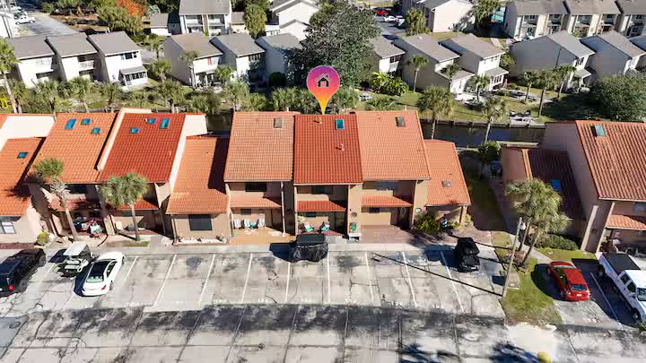Aerial view of the townhome with red tile roof and parking